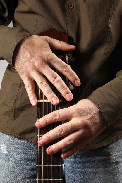 A detailed close-up of a guitarist's hands playing an extended-range guitar, showcasing the intricate fingerwork and palm-muting technique characteristic of djent music. The focus is on the strings and the guitarist's precise movements.