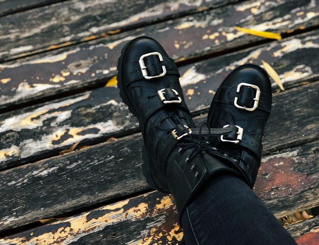 Close-up shot of a pair of black combat boots with silver buckles and thick soles, reflecting the durable and practical footwear commonly seen at heavy metal concerts.