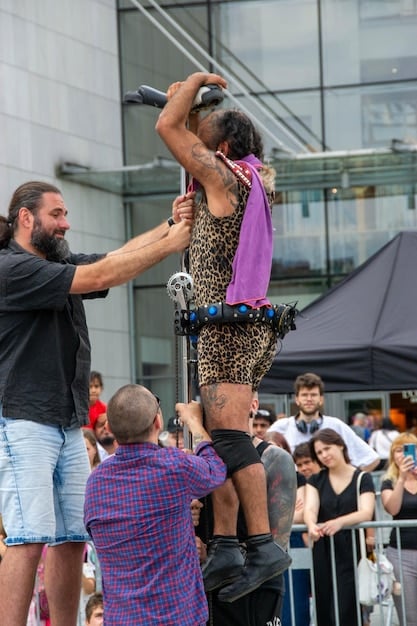 A wide shot of a diverse group of people holding up a crowd surfer towards the bands performing on stage at a show.