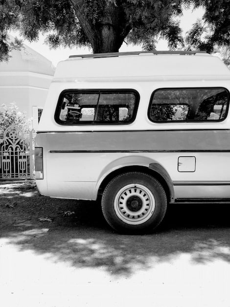 An exterior shot of a well-equipped tour van or SUV parked in front of a concert venue, with band stickers and travel gear visible. The image embodies the ideal road trip vehicle for a heavy metal band or dedicated fans.