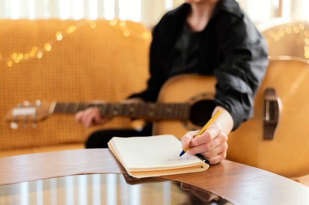 A close-up shot of a band member pensively writing lyrics in a notebook, illuminated by the warm glow of a lamp. The background is softly blurred, creating a sense of intimacy and focus on the creative process.